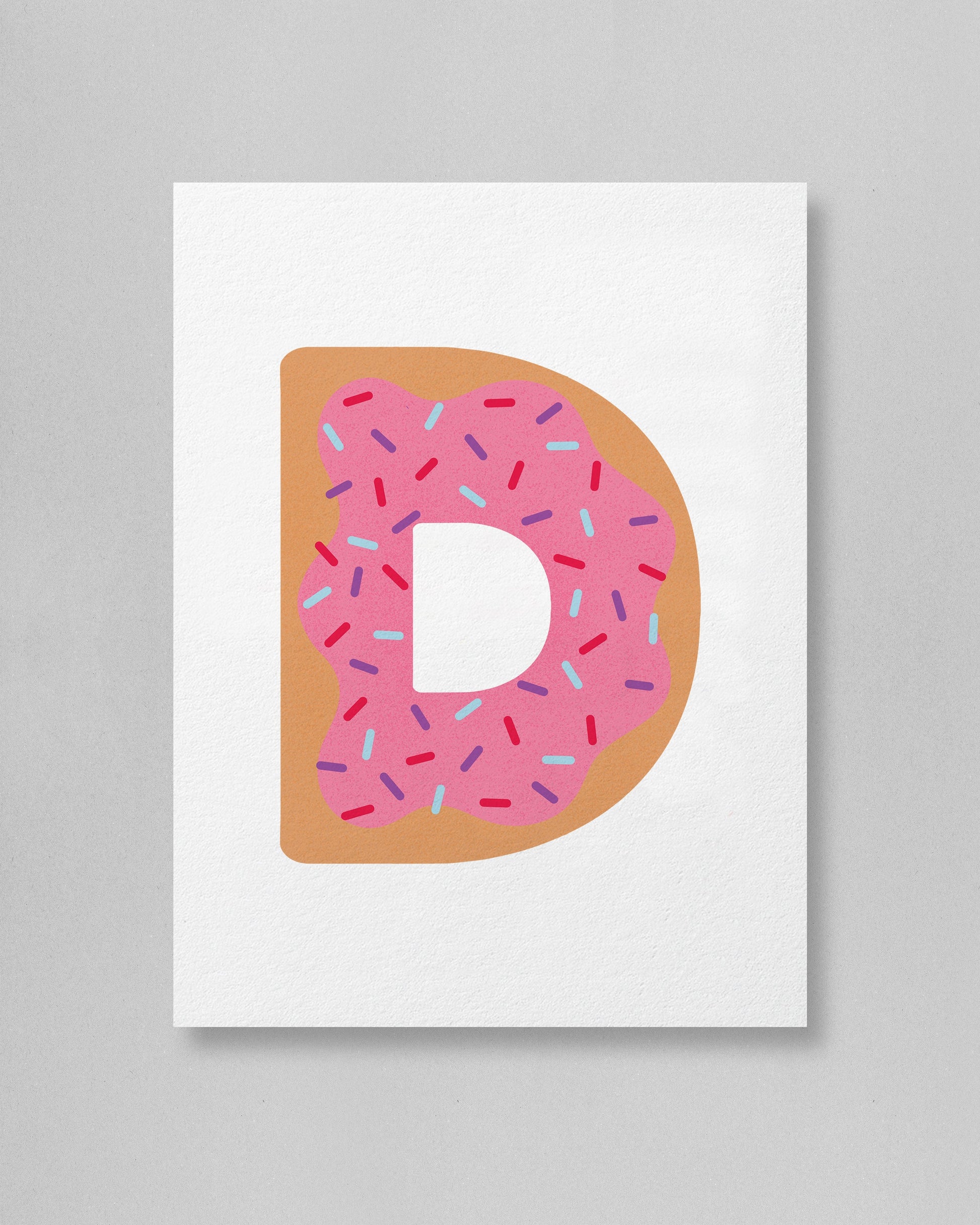 Letter 'D' shaped like a donut with pink icing and sprinkles on a white background