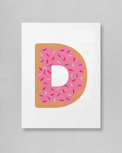 Letter 'D' shaped like a donut with pink icing and sprinkles on a white background
